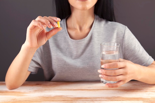 Close up cropped image millennial mixed race girl holding pill and glass of fresh water