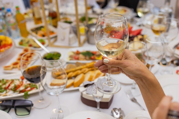 Close up cropped shot of the table during romantic dinner with lover s hands with glasses of wine and food.