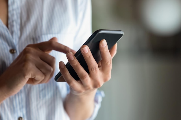 Photo close up cropped of woman holding smartphone in hand typing on screen writing message in social network young female chatting or shopping online browsing mobile device apps ordering in internet