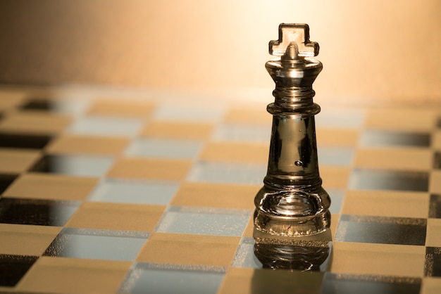 Close up of the Crystal king chess on the chess board with sunlight background 