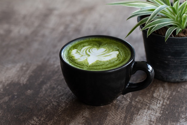 Close up a cup of Matcha green tea latte on wooden table background