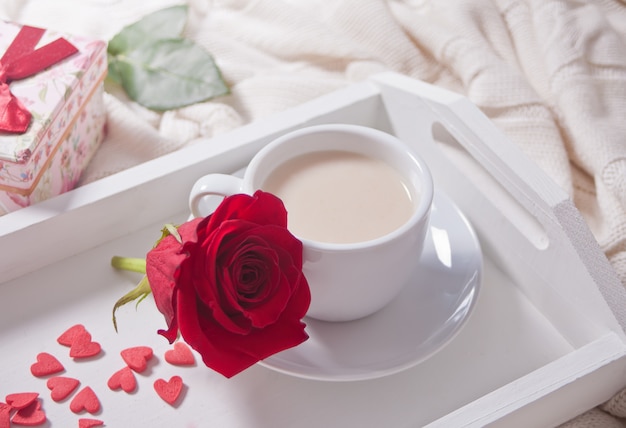 Close up of cup of tea with red rose on the white tray