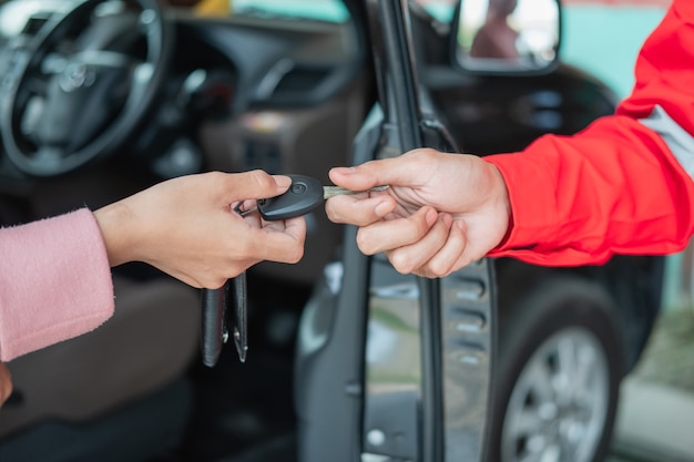 Close up of customer hand giving car keys to mechanic with workshop background