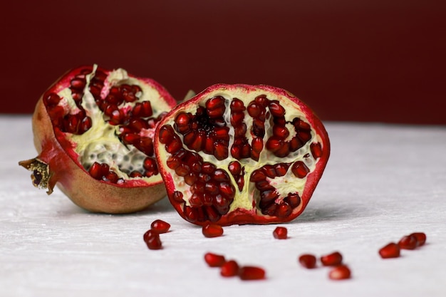 close up of a cut pomegranate on white table, red background with copy space