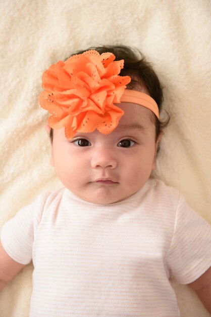 Close up of cute little Asian baby wearing orange flower head