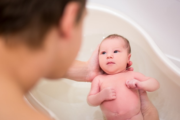 close up of cute newborn baby taking a bath in fathers hands