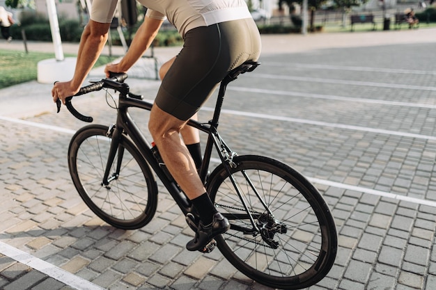 Close up of cyclist in sport clothes biking outdoors during summer time Focus on muscular male legs Outdoors workout