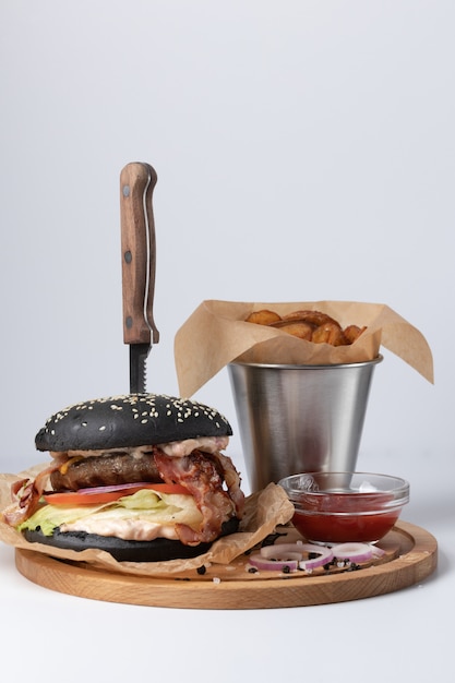 Close-up of a dark burger with potato wedges