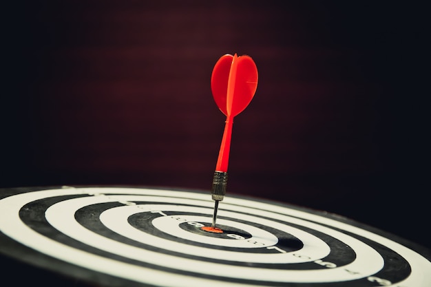 Close-up dart board with arrow hitting in the target center.