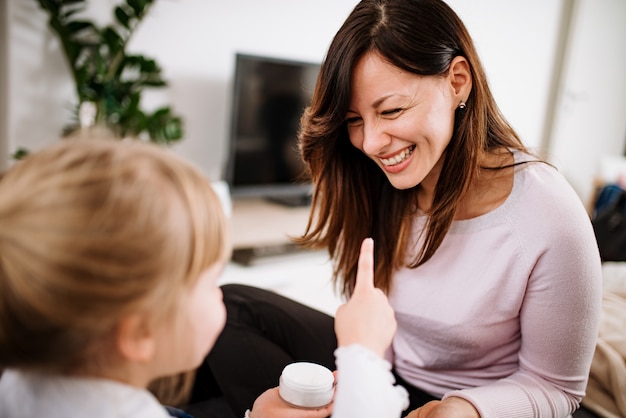 Close-up of daughter putting cream on mother's face at home