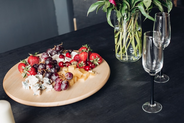 Close-up of delicious food plate full of seasoned fresh berries, fruit and cheese.