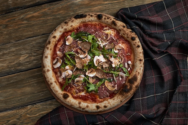 Close up on delicious freshly baked small pizza with melted cheese mushrooms and basil