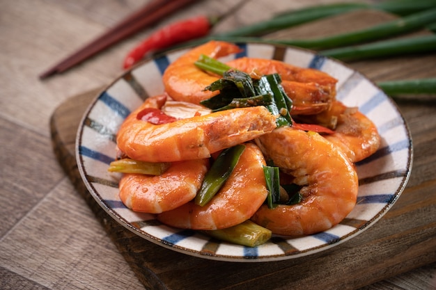 Close up of delicious homemade pan-fried shrimp in a plate on dark wooden table surface.