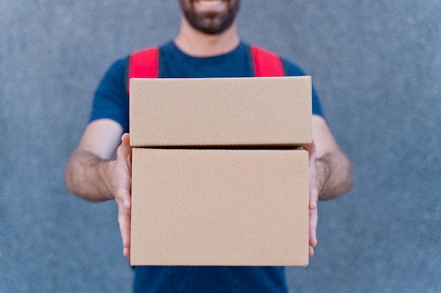 Close up of delivery man delivering parcel box. Courier service concept. Horizontal view of unrecognizable rider delivering home a package.