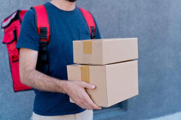 Close up of delivery man delivering parcel box. Courier service concept. Horizontal view of unrecognizable rider delivering home a package.