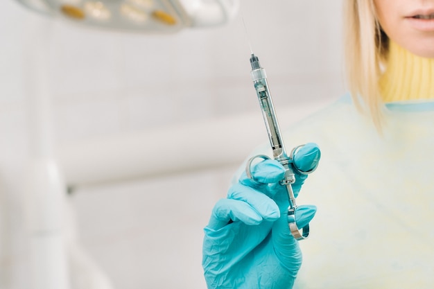 Close-up of a dentist's hand holding an injection syringe for a patient in the office.