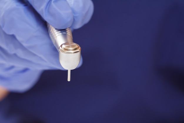 Close-up dentist's hand in a latex glove with high-speed dental handpiece on blurred background. Medical tools concept. Shallow depth of fiel.