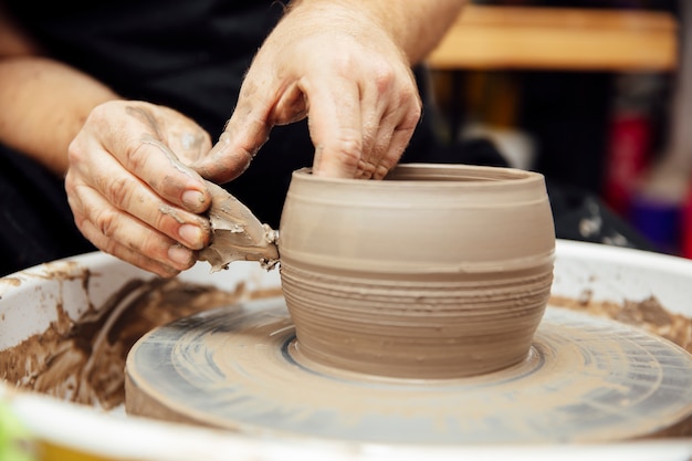 Close up detail view at an artist makes clay pottery on a spin wheel