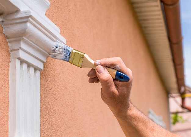 Photo close up details of painting walls industrial worker using roller and other tools for painting