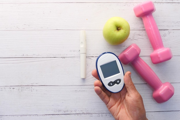 Close up of diabetic measurement tools apple and dumbbell on table