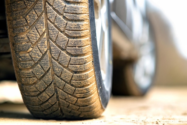 Close up of dirty car wheel with rubber tire covered with yellow mud