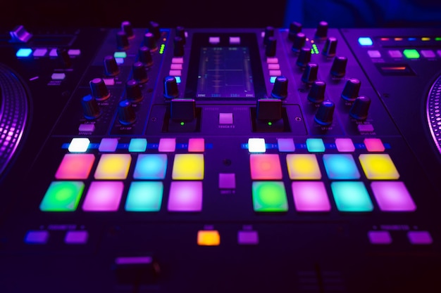 Close up of DJ mixing console in party light