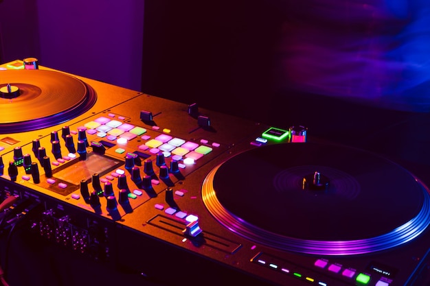 Close up of dj mixing console in party light