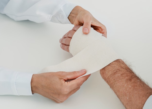 Close-up doctor bandaging hand of patient