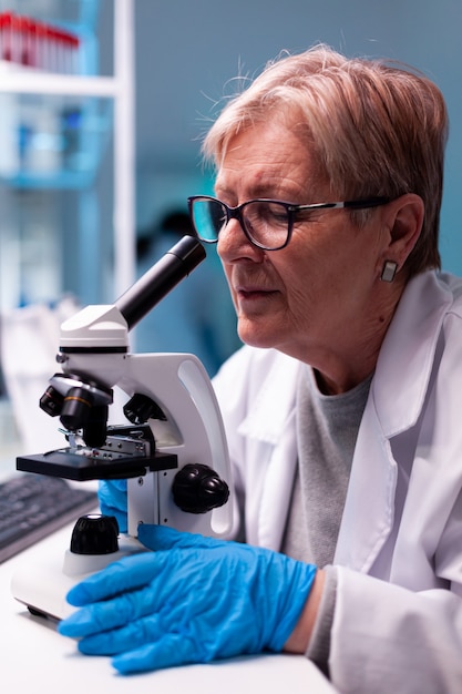 Close up of doctor chemist scientist analyzing sample in lab coat with microscope