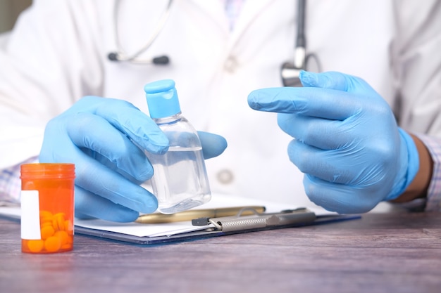 Close up of doctor hand in latex gloves holding hand sanitizer