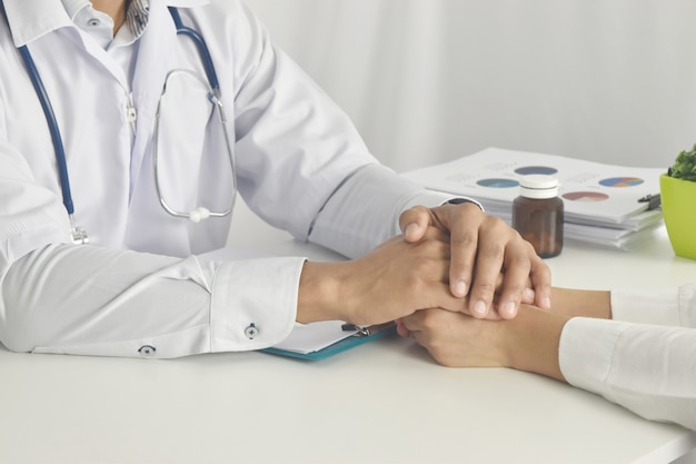 Close up of doctor hand reassuring her female patient at hospital Doctor holding hands of patient