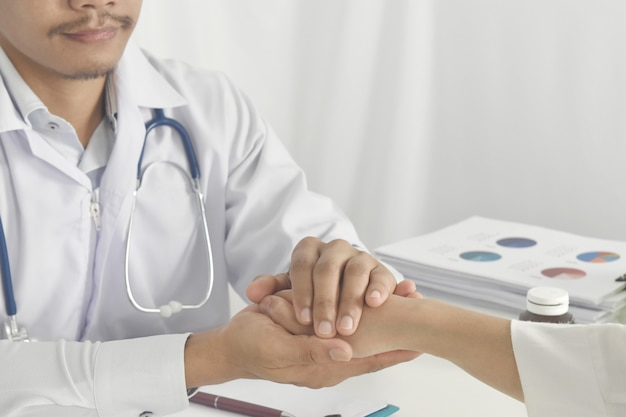 Close up of doctor hand reassuring her female patient at hospital Doctor holding hands of patient