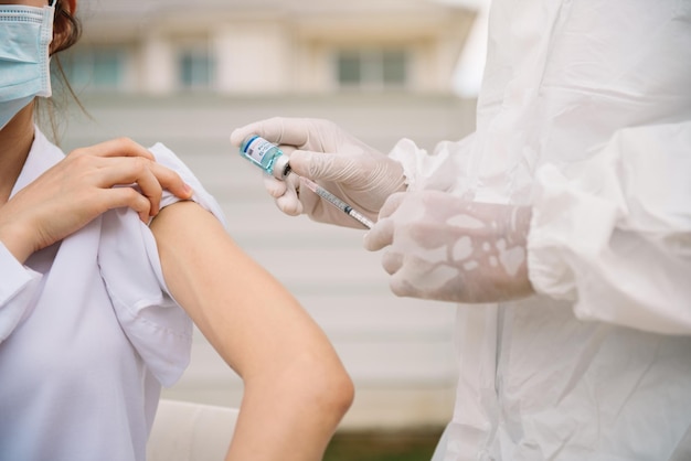 Close up doctor holding syringe and using cotton before make injection to patient in medical mask. Covid-19 or coronavirus vaccine.