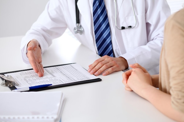 Close-up of a doctor man  holding application form while consulting patient