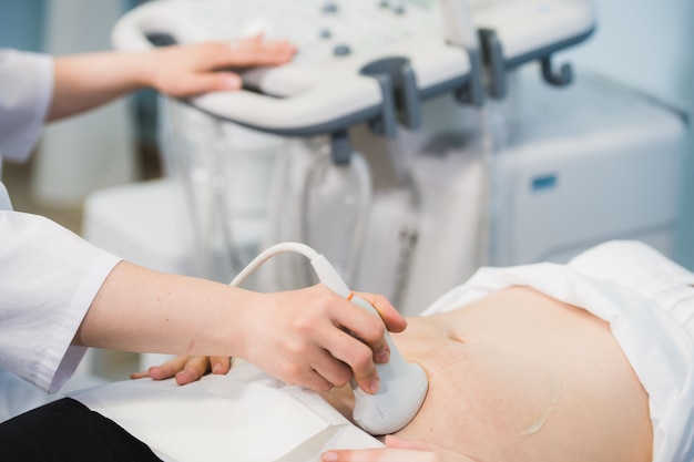 Close-up Of Doctor Moving Ultrasound Probe On Pregnant Woman's Stomach In Hospital