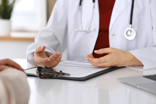 Close up of a doctor and patient hands while discussing medical records after health examination