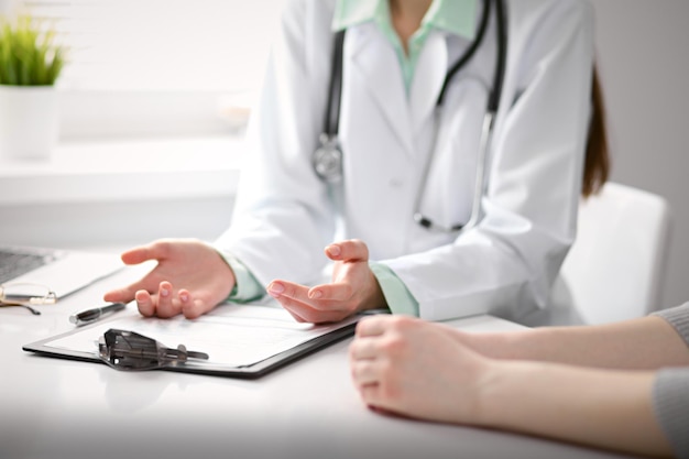 Close up of doctor and patient sitting at the desk near the window in hospital