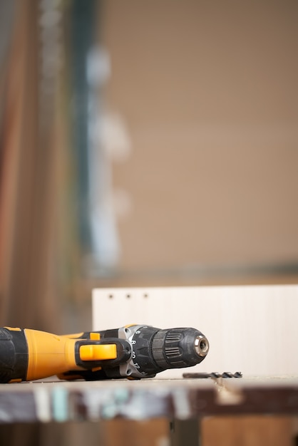 Close-up drill with wooden board in workshop