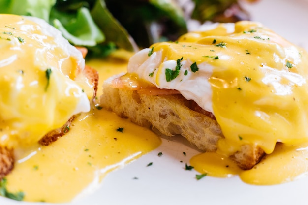 Close up Egg benedict served with salad in white plate.