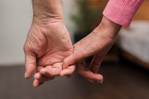 Close-up elderly couple holding hands