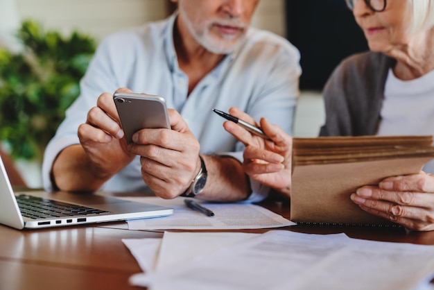 Close up of elderly couple sitting at table in living room manage household document