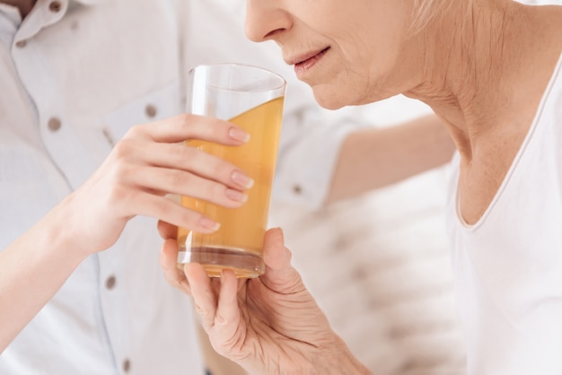 Close up. Elderly woman drinking juice in hospital.