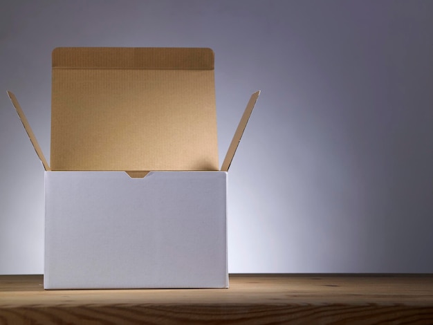 Photo close-up of empty cardboard box on table against gray background