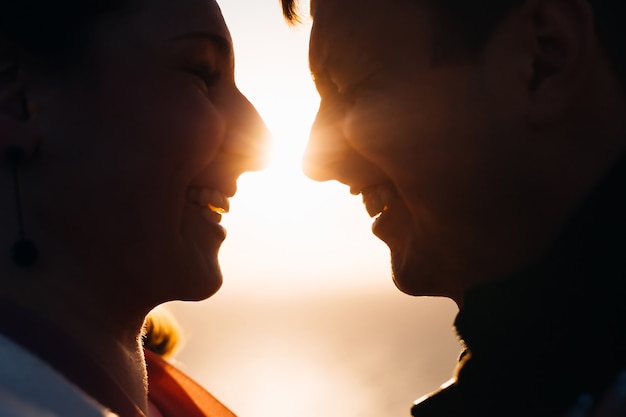 A close-up face of the couple in love who sincerely laugh and between them are sun rays