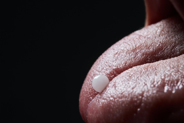 Close up of face of young woman taking drug The drug addict is standing and putting a pill into her mouth