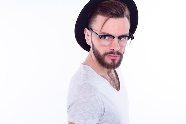 Close up fashion portrait of young bearded man Smiling hipster guy Handsome man in stylish hat Brutal bearded boy in trendy glasses