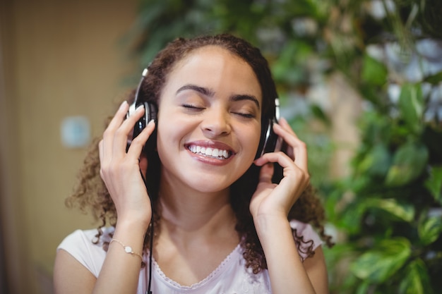 Close-up of female business executive listening music on headphone