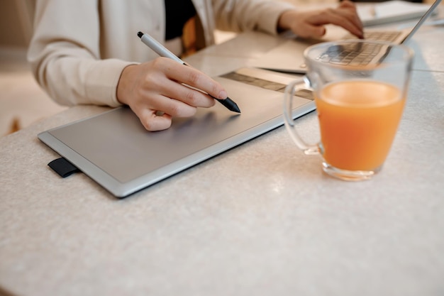 Close up of female designer works in home office drawing on graphic tablet Freelancer working on project watching movie on computer studying blogging relaxing and chatting online