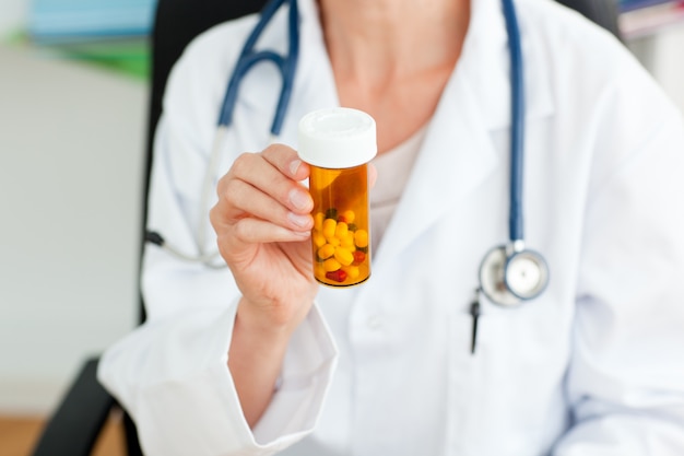 Close-up of a female doctor holding pills into the camera