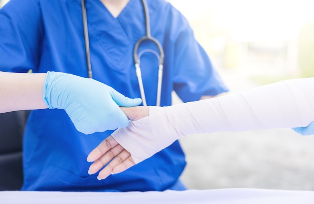 Close-up of female doctor putting a bandage on injured hand upper limb of patient.